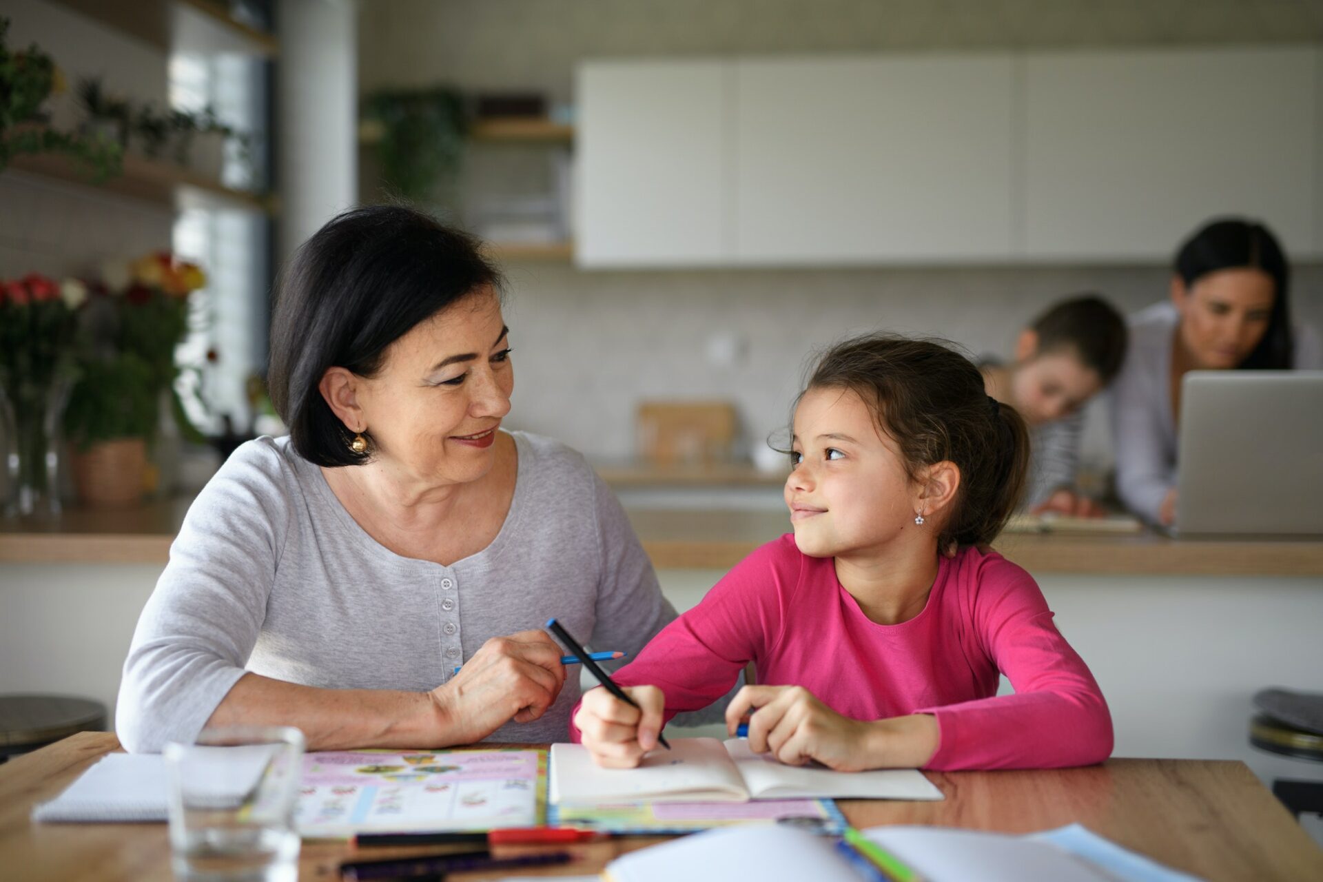 Small girl with grandmother doing homework indoors at home